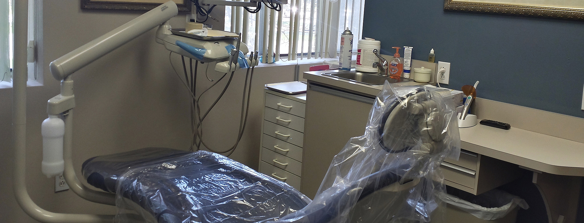 Dental office with a dental chair and equipment, set against a blue wall.