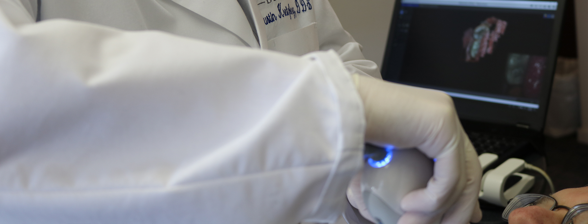 A medical professional in a lab coat using a computer with a blue light.