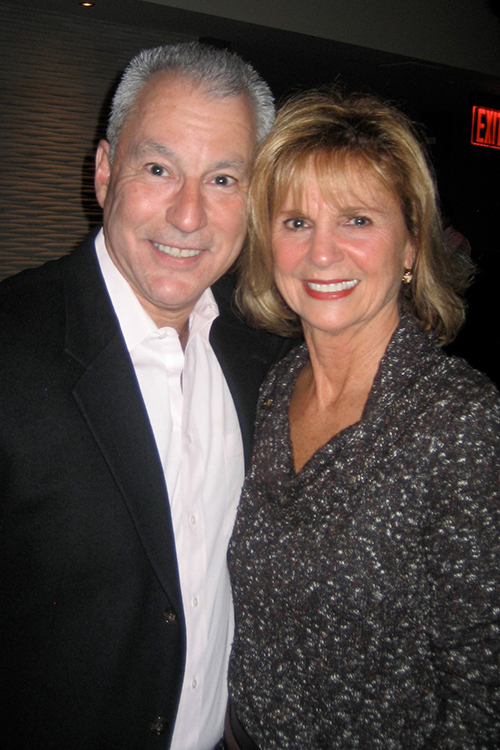 Man and woman posing for a photo together, with the man wearing a dark suit and tie.