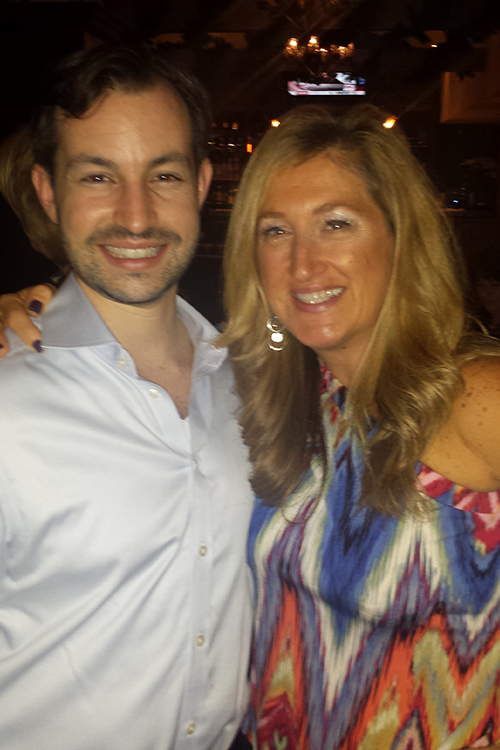 The image shows a man and a woman posing together at an event.