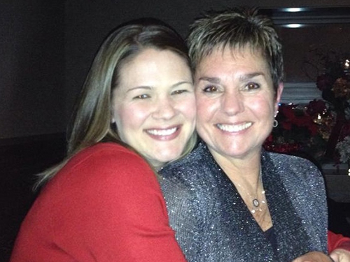 The image shows two women, one older and one younger, embracing each other in a warm smile.