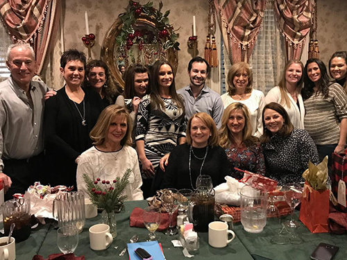 A group of people posing for a photo at a holiday gathering, with a festive atmosphere and Christmas decorations in the background.