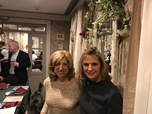 Two women standing together, smiling at the camera.