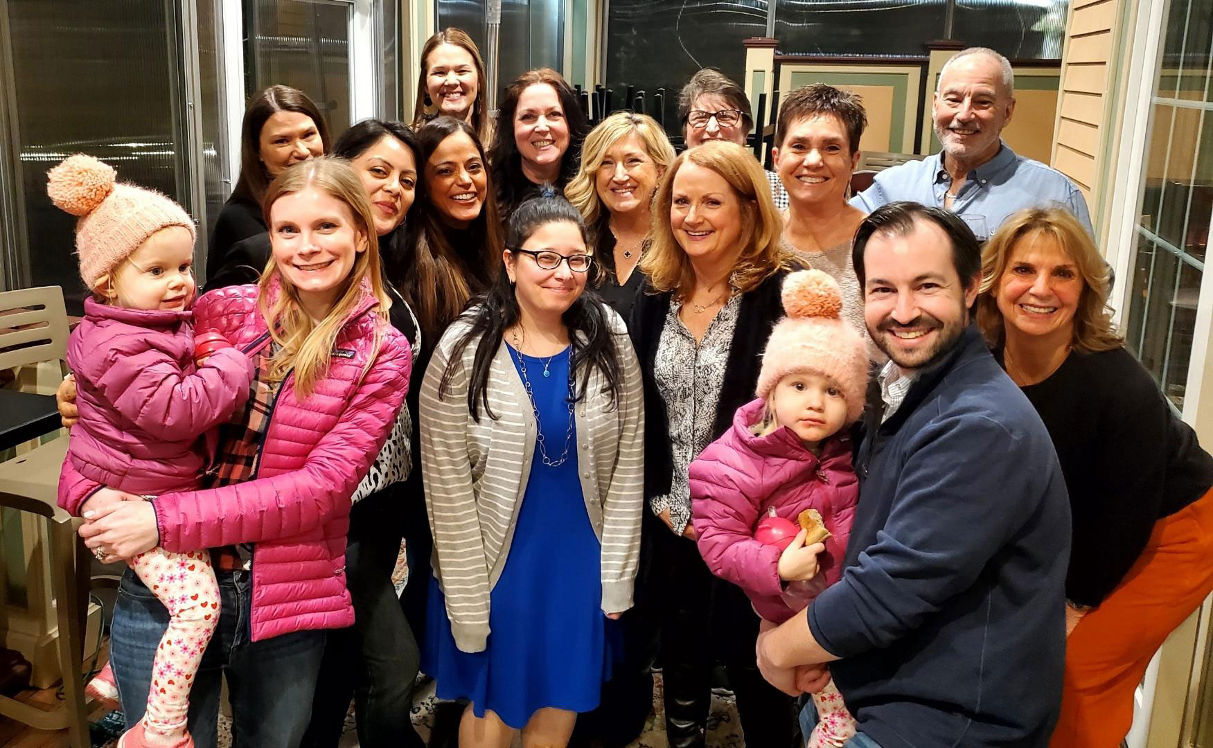 A group of people posing for a photo in front of a restaurant, with some individuals holding children.