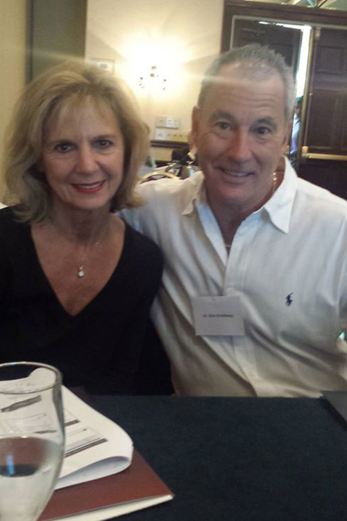 The image shows a man and a woman sitting together at a table, likely in a professional or formal setting.