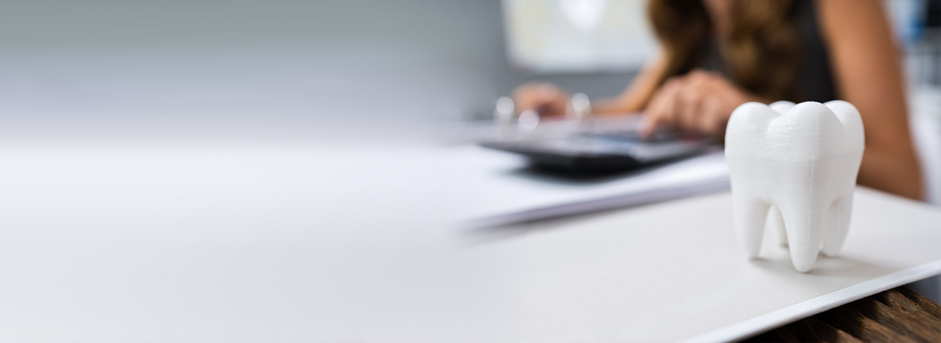 A woman using a laptop at a desk with a toothbrush holder on it.