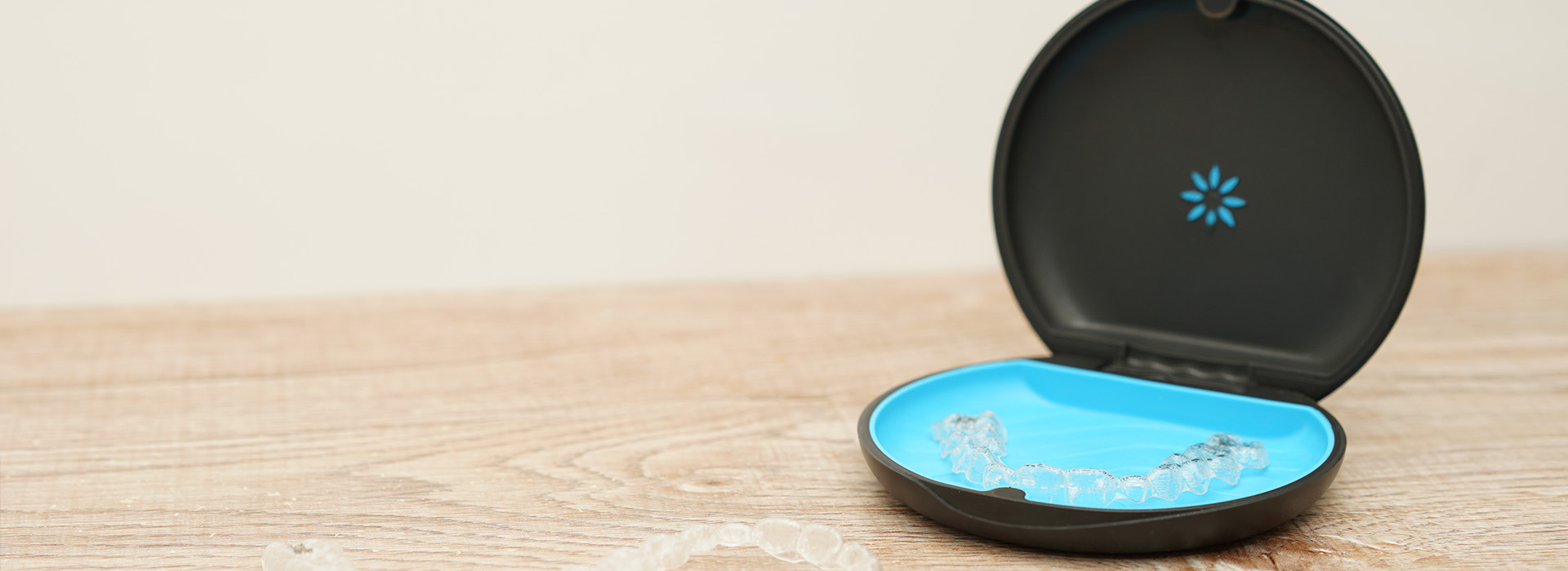 A compact Wi-Fi router with an antenna and a blue base, placed on a wooden surface.