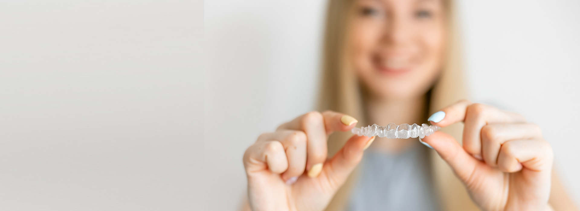 A woman s hand holding a small, clear object with text inside, likely a piece of jewelry or an award, against a blurred background.