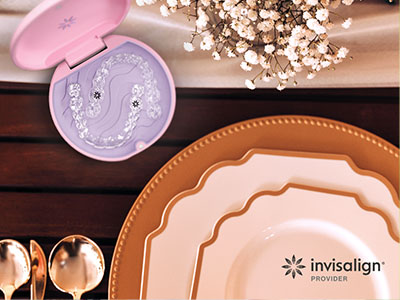 An advertisement for Invisalign, featuring a close-up of a pink oral appliance and a collection of ceramic plates on a wooden table.