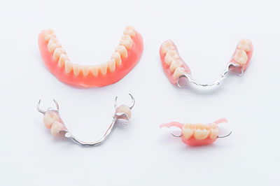 The image shows a collection of dental braces displayed on a white background, with one set featuring red teeth and another set with silver or white teeth.