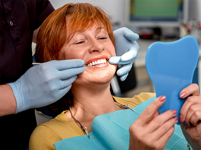 A woman in a dental chair receiving oral care, with a dental professional performing the procedure.