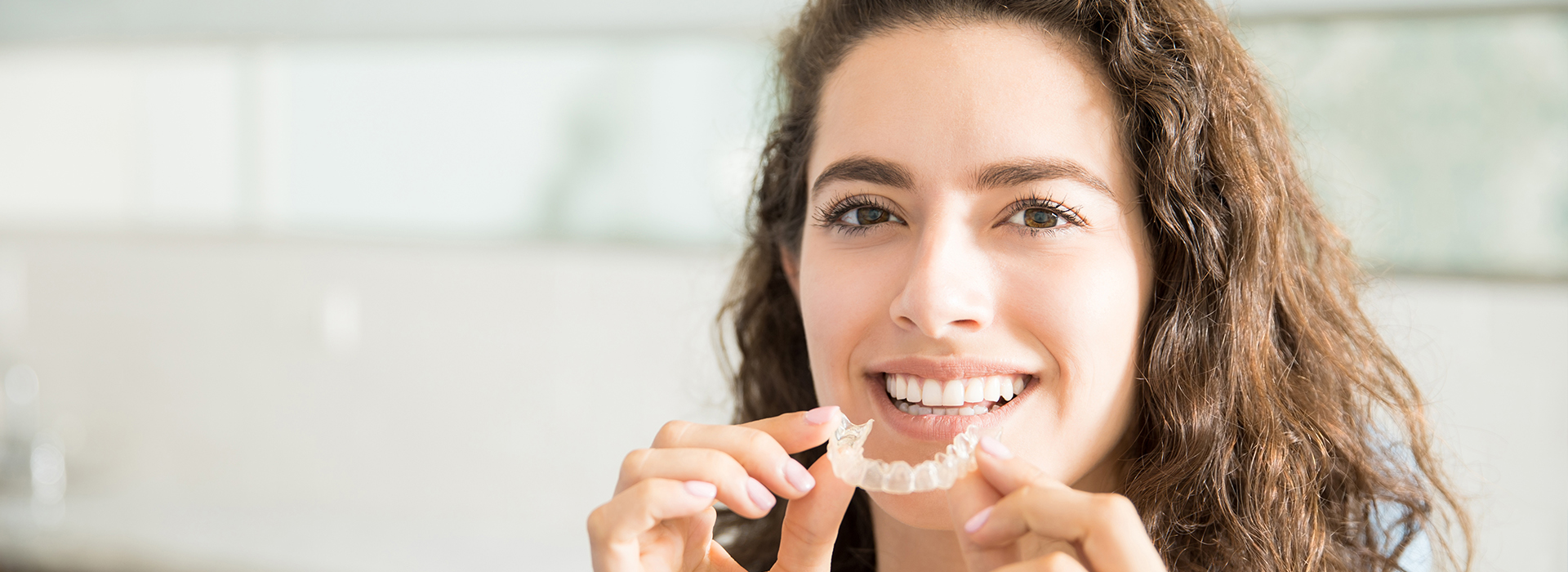 The image shows a person with their mouth open, appearing to be brushing teeth or eating, against a blurred background that suggests an indoor setting.