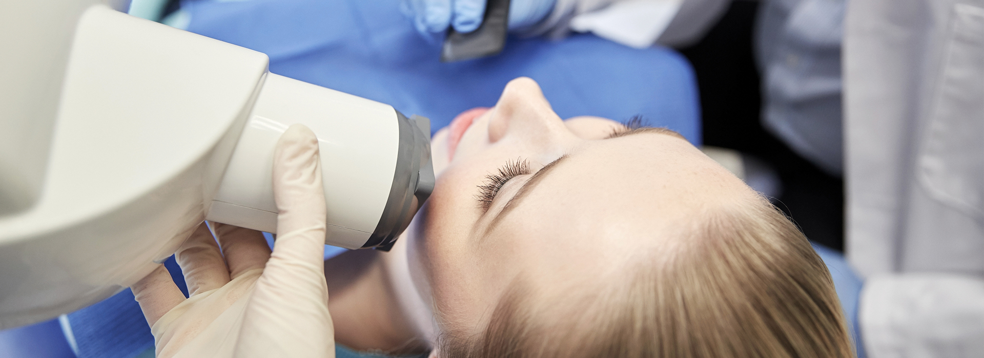 Woman receiving dental implant procedure, with focus on the surgical drill in her mouth.