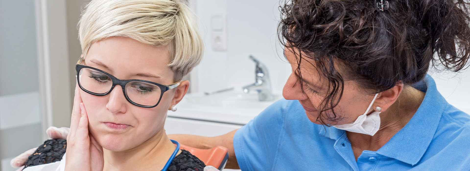 The image shows a woman with glasses and a man in a blue shirt receiving dental care from a dentist.