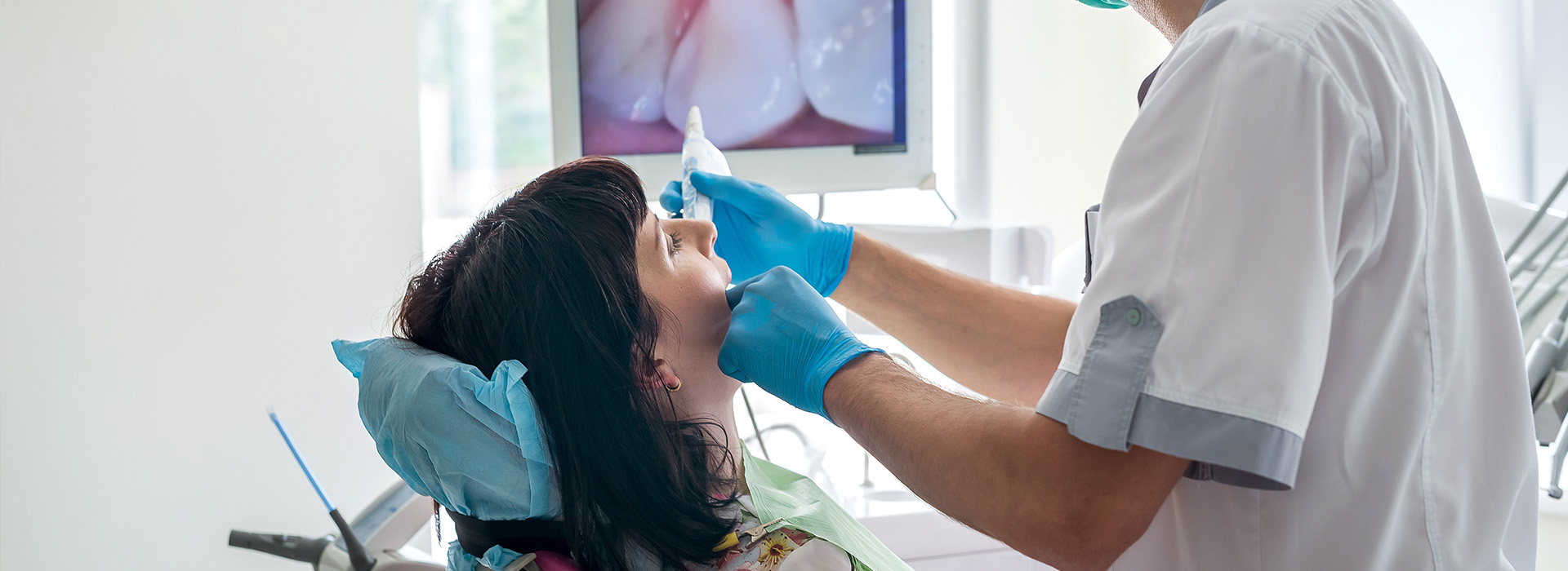 A dentist is performing a dental procedure on a patient, with the dentist wearing gloves and a surgical mask.