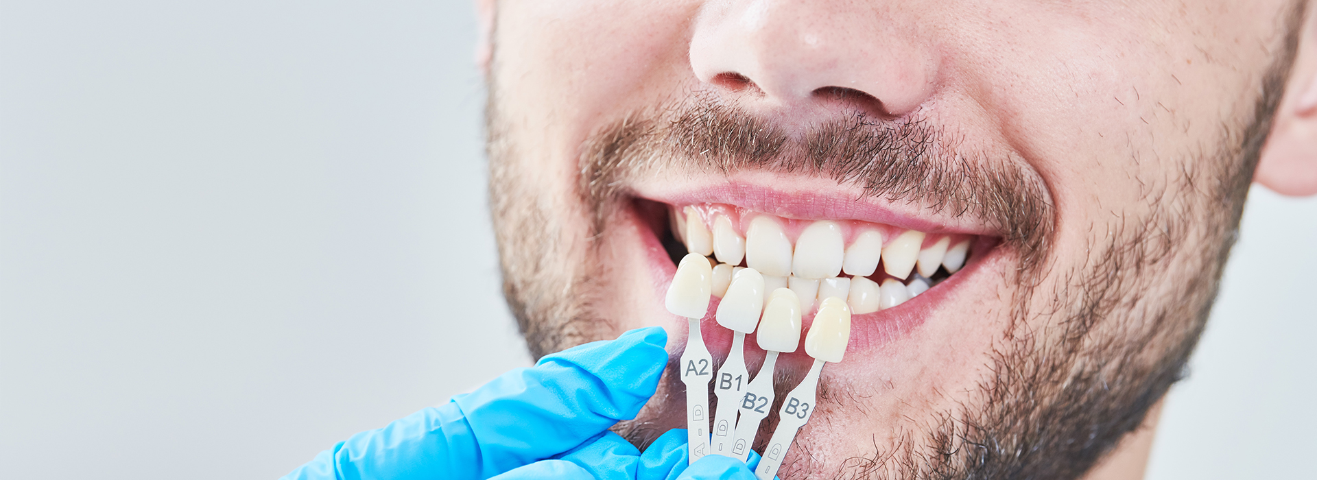 The image shows a person with a toothy smile, wearing a blue surgical mask and holding a toothbrush with toothpaste.