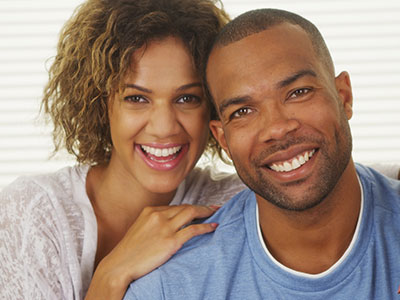 A man and a woman share a joyful moment, smiling broadly at the camera.