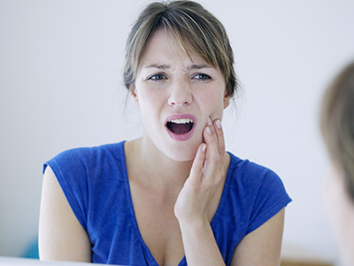 A woman with a concerned expression is holding her hand to her mouth, possibly in response to an unexpected situation or comment.