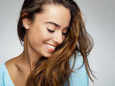 A young woman with long hair, wearing a light blue top, smiling gently at the camera.