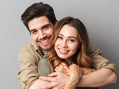 A man and woman embrace warmly, both smiling broadly.