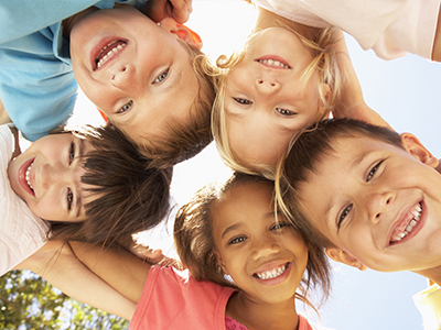 A group of children in a joyful pose, smiling and looking at the camera.