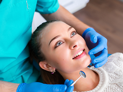 A dental hygienist performing a cleaning procedure on a patient s teeth.