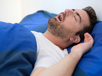 Man lying in bed, eyes closed, likely sleeping or resting.