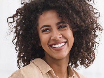 A woman with curly hair, smiling warmly at the camera.